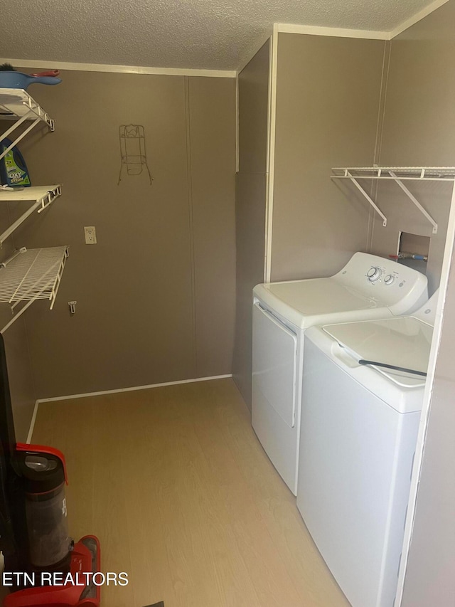 laundry room featuring washer and dryer, a textured ceiling, and light hardwood / wood-style flooring