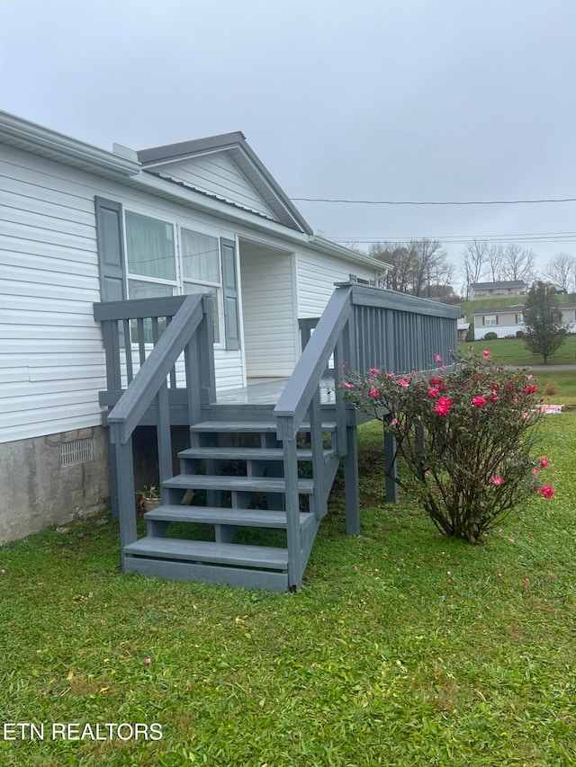 entrance to property featuring a lawn and a wooden deck