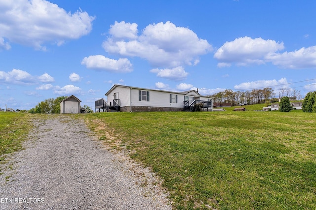 exterior space featuring a front lawn, driveway, an outbuilding, and a storage unit