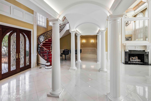 foyer featuring a high end fireplace, french doors, ornamental molding, and light tile patterned flooring