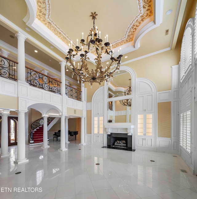 unfurnished living room with ornate columns, crown molding, a premium fireplace, and a high ceiling