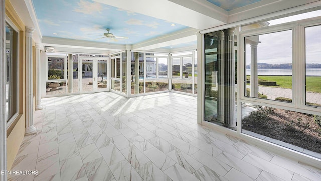 unfurnished sunroom with ceiling fan and a water view