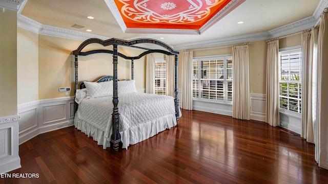 bedroom with a raised ceiling, dark hardwood / wood-style floors, and ornamental molding