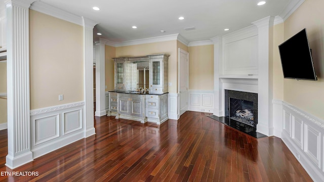 unfurnished living room with ornamental molding, decorative columns, dark wood-type flooring, and a premium fireplace