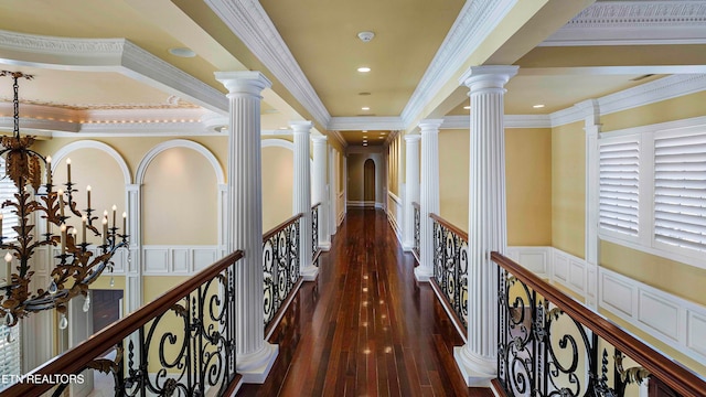 hallway with dark hardwood / wood-style floors, a raised ceiling, crown molding, and an inviting chandelier