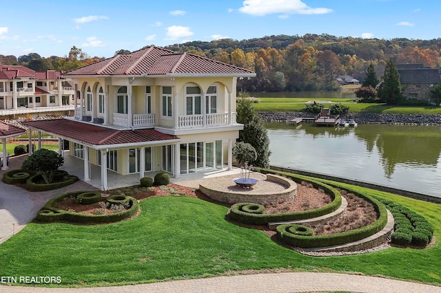 back of house with a balcony, a lawn, a patio area, and a water view