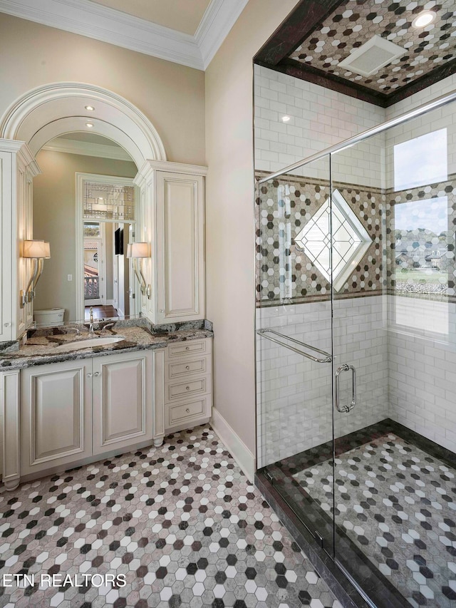 bathroom featuring a shower with door, vanity, and ornamental molding