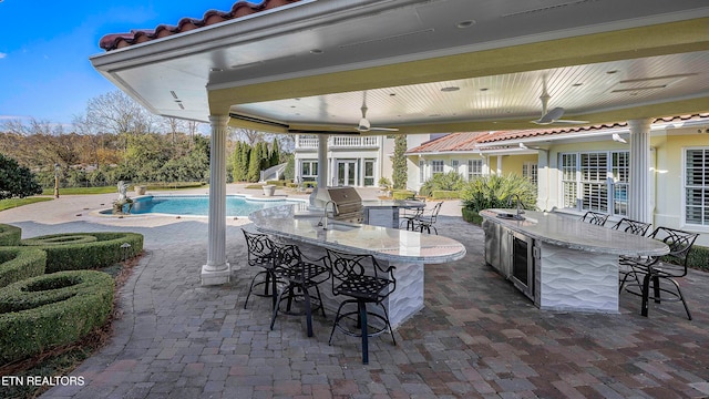 view of patio featuring wine cooler, ceiling fan, an outdoor wet bar, and an outdoor kitchen