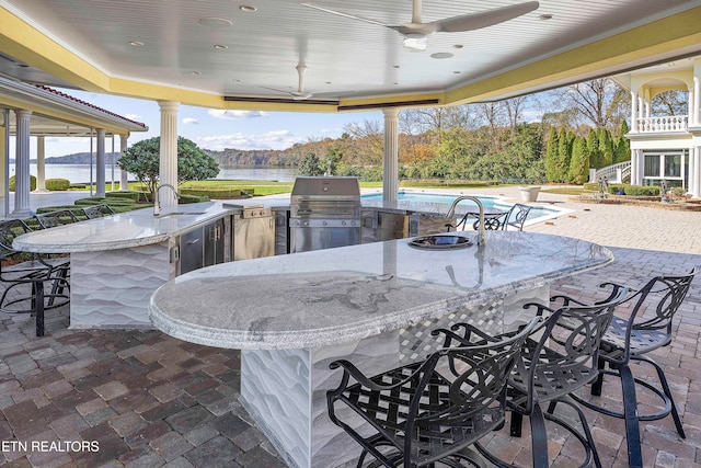 view of patio featuring area for grilling, ceiling fan, an outdoor wet bar, and an outdoor kitchen