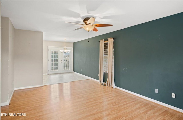 unfurnished room with ceiling fan with notable chandelier and light hardwood / wood-style floors