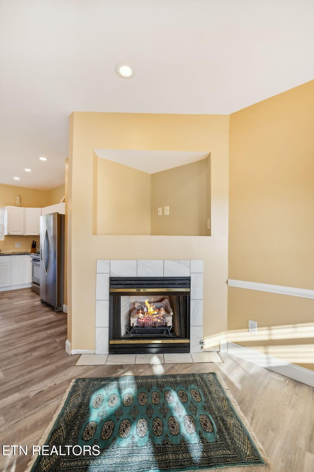 room details with hardwood / wood-style flooring, stainless steel appliances, and a tiled fireplace