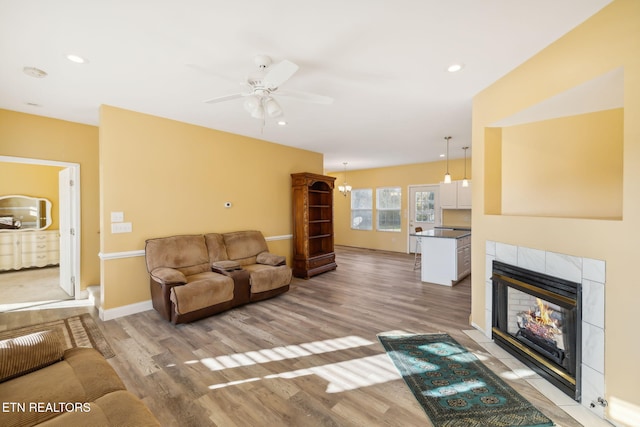 living room featuring light hardwood / wood-style floors, ceiling fan, and a tiled fireplace