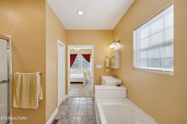 bathroom featuring tile patterned flooring, vanity, a healthy amount of sunlight, and a tub