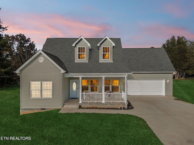 cape cod-style house featuring covered porch, a garage, and a lawn