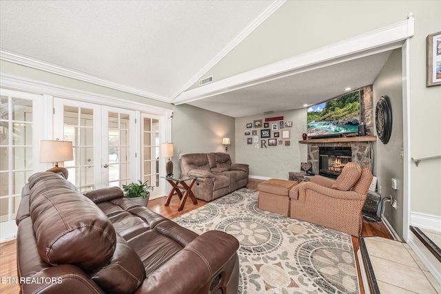 living room with lofted ceiling, a fireplace, light wood-type flooring, and french doors