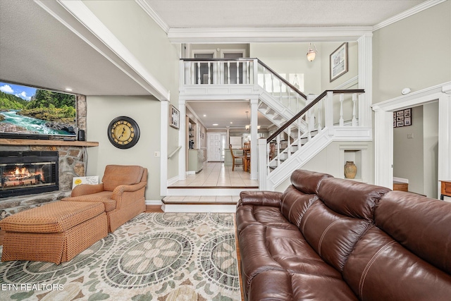 living room with a towering ceiling, a fireplace, light tile patterned floors, and crown molding