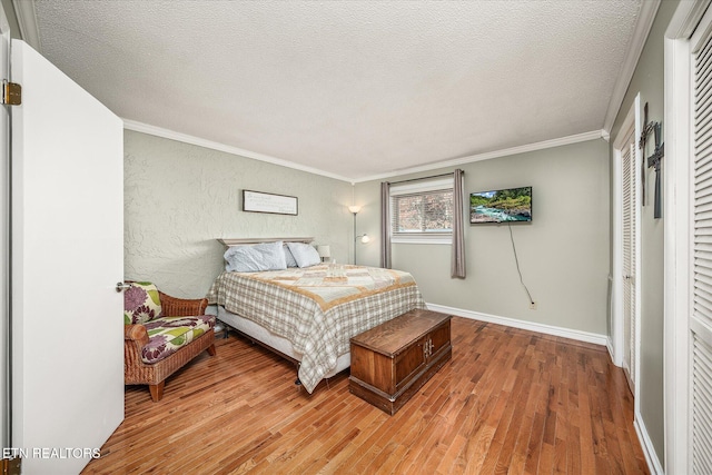 bedroom with a textured ceiling, hardwood / wood-style floors, and crown molding