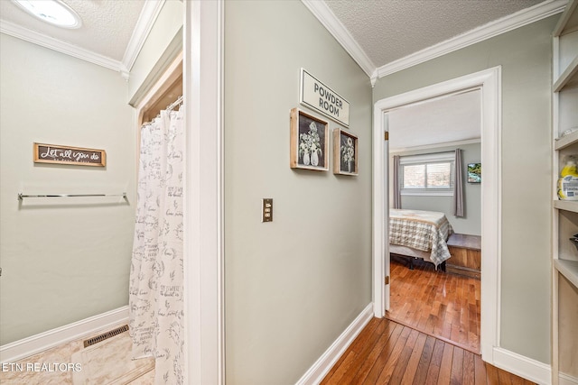 corridor featuring a textured ceiling, ornamental molding, and wood-type flooring