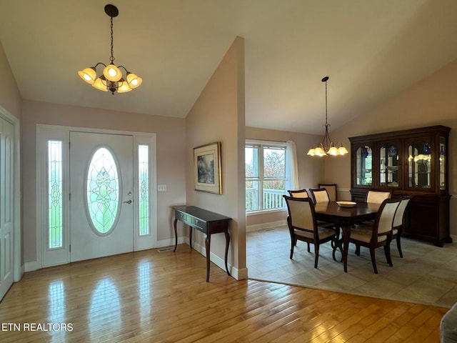 foyer entrance with light hardwood / wood-style flooring, lofted ceiling, and an inviting chandelier