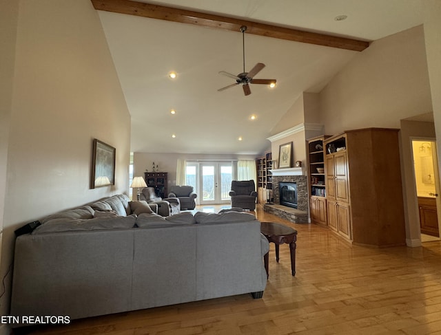 living room featuring beam ceiling, ceiling fan, a stone fireplace, high vaulted ceiling, and light wood-type flooring