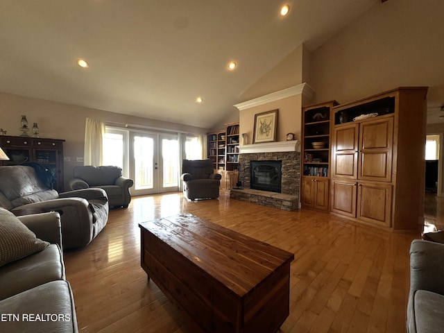 living room featuring a fireplace, light hardwood / wood-style flooring, high vaulted ceiling, and french doors