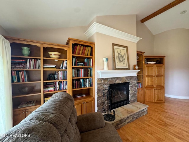 living room featuring vaulted ceiling with beams, light wood-type flooring, and a fireplace