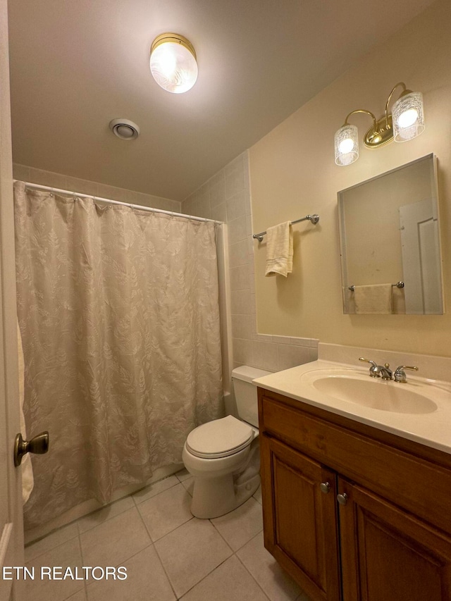 bathroom featuring tile patterned flooring, vanity, toilet, and curtained shower