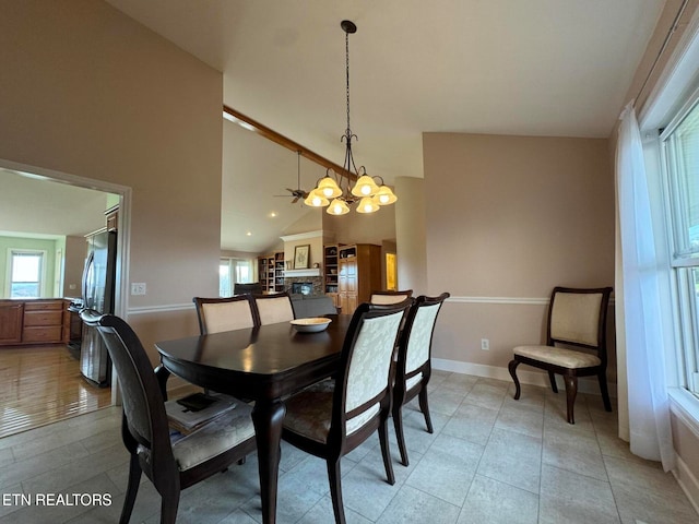 dining space featuring ceiling fan with notable chandelier, lofted ceiling, and light tile patterned floors