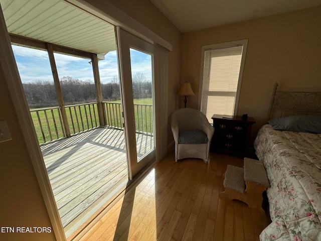 bedroom with multiple windows, wood-type flooring, and access to exterior