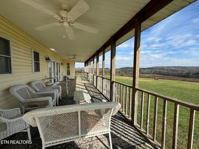 wooden terrace featuring a yard, a rural view, and ceiling fan