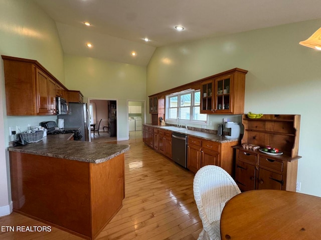 kitchen with sink, stainless steel appliances, independent washer and dryer, kitchen peninsula, and light hardwood / wood-style floors