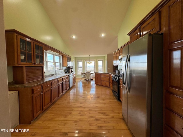 kitchen with sink, hanging light fixtures, stainless steel appliances, light hardwood / wood-style flooring, and high vaulted ceiling