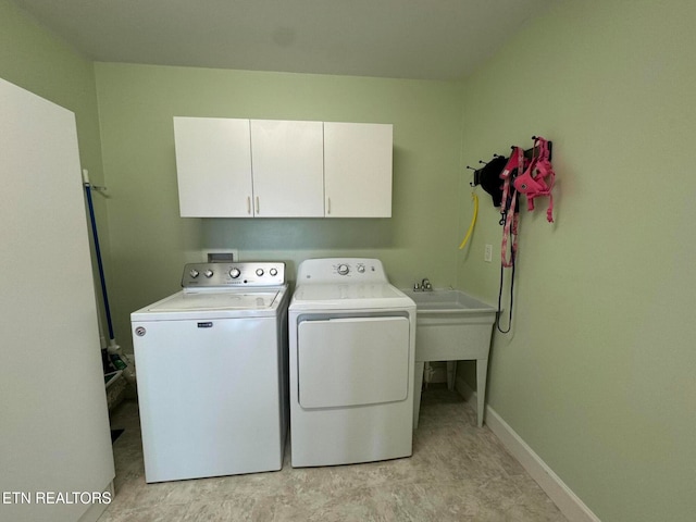 clothes washing area with washing machine and clothes dryer, sink, and cabinets