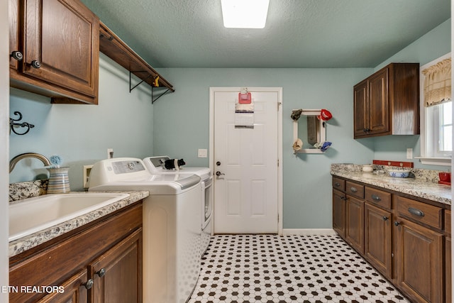 washroom featuring a textured ceiling, cabinets, separate washer and dryer, and sink