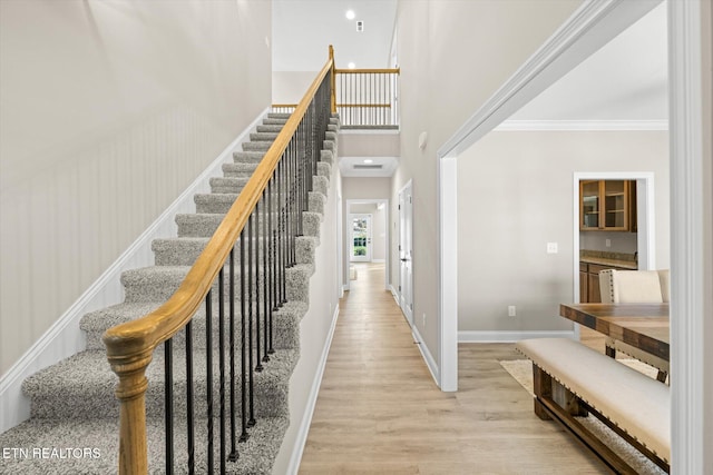 staircase featuring wood-type flooring and ornamental molding