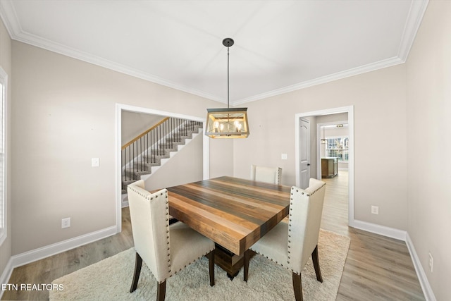 dining area with light hardwood / wood-style floors, an inviting chandelier, and crown molding