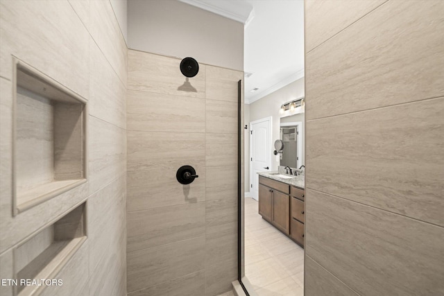 bathroom featuring a tile shower, vanity, and crown molding