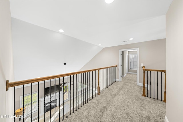 hall featuring light colored carpet and lofted ceiling