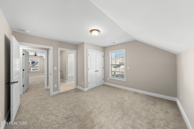 unfurnished bedroom featuring light colored carpet, vaulted ceiling, and a closet