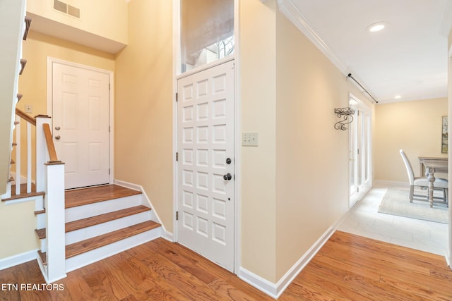 foyer entrance with hardwood / wood-style flooring and ornamental molding