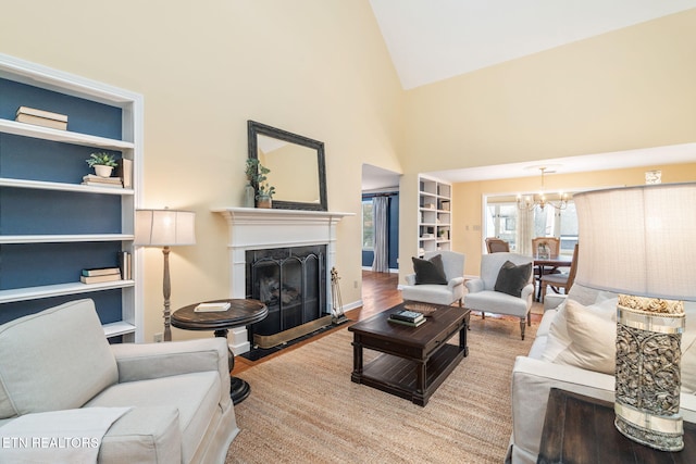 living room featuring an inviting chandelier, built in features, high vaulted ceiling, and light hardwood / wood-style flooring