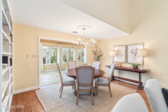 dining space featuring hardwood / wood-style floors and an inviting chandelier