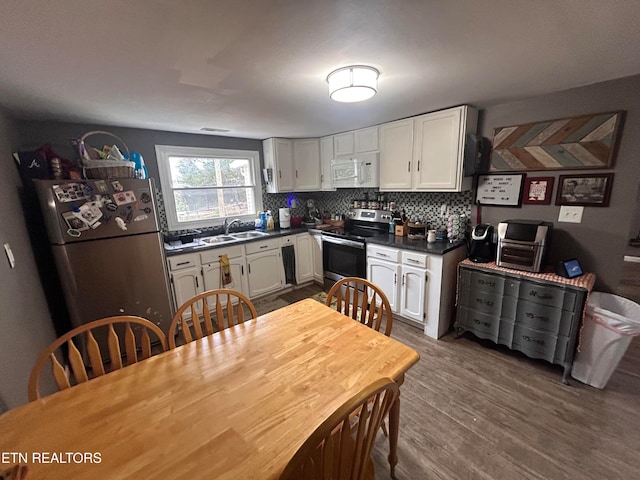 kitchen with white cabinetry, sink, stainless steel appliances, and wood-type flooring