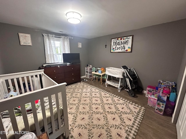 bedroom featuring hardwood / wood-style floors and a nursery area