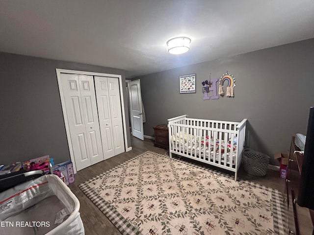 bedroom featuring a crib, hardwood / wood-style floors, and a closet