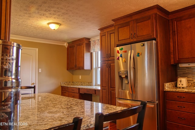 kitchen featuring a textured ceiling, stainless steel fridge, light stone countertops, and ornamental molding