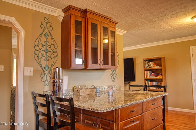 kitchen featuring light stone counters, light hardwood / wood-style flooring, a textured ceiling, and ornamental molding