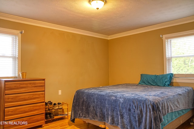 bedroom featuring hardwood / wood-style floors, a textured ceiling, and crown molding