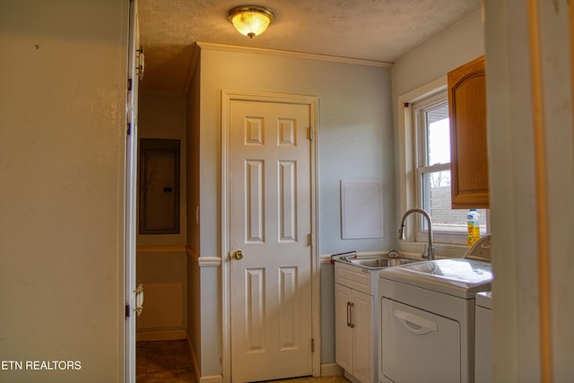 clothes washing area featuring washer and clothes dryer, cabinets, electric panel, sink, and a textured ceiling