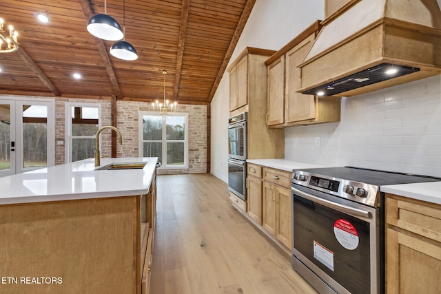 kitchen featuring stainless steel appliances, a center island with sink, hanging light fixtures, and a notable chandelier